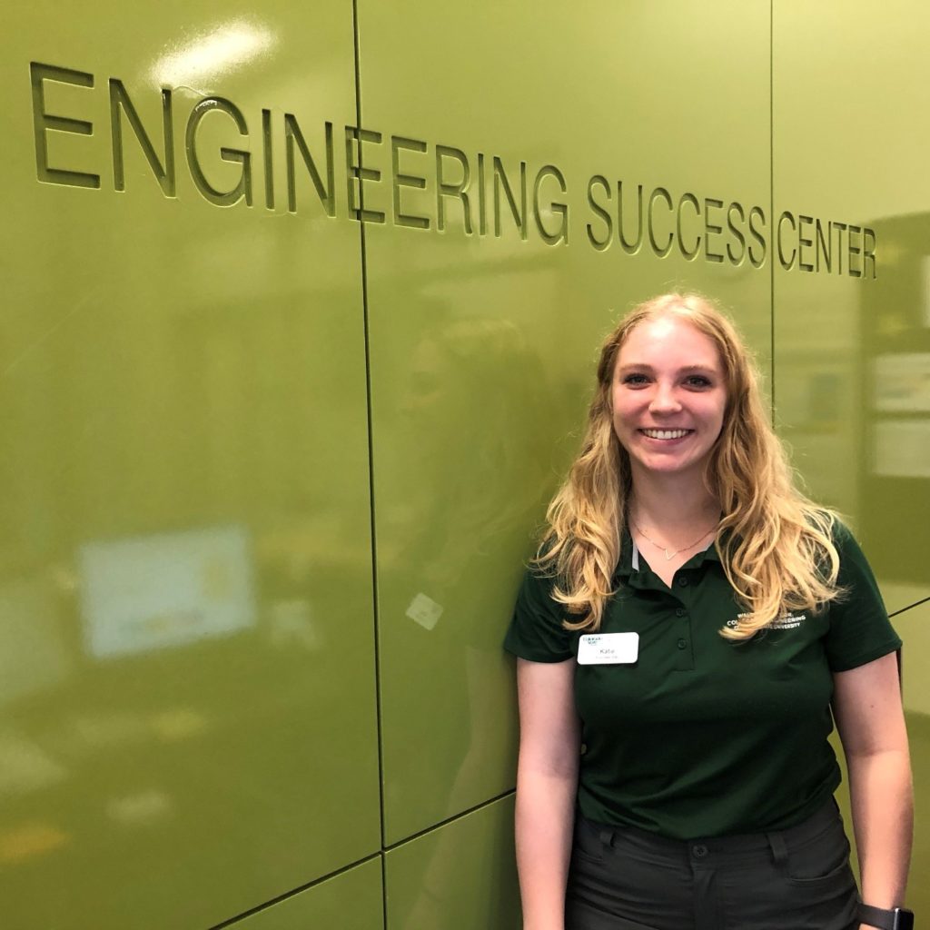 Katie Brown, a CSU engineering student standing by a green wall.