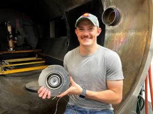 Seth Thompson holds the 1.5 kW thruster inside the vacuum chamber where it’s tested. 