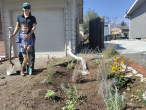 Jessica Thrasher and her son Austin stand near a completed rain garden in Denver.
