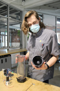 A student researcher works with a prototype wastewater sampling system at the Rapid Prototyping Lab