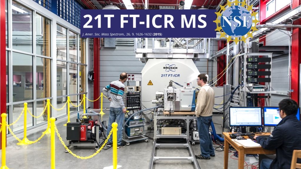 A banner reading "21T FT-ICR MS" hangs above the mass spectrometer at the National High Magnetic Field Laboratory as several researchers work on the equipment.