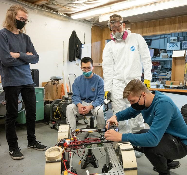 Students prepare to test the chassis of their mining robot in a laboratory. 