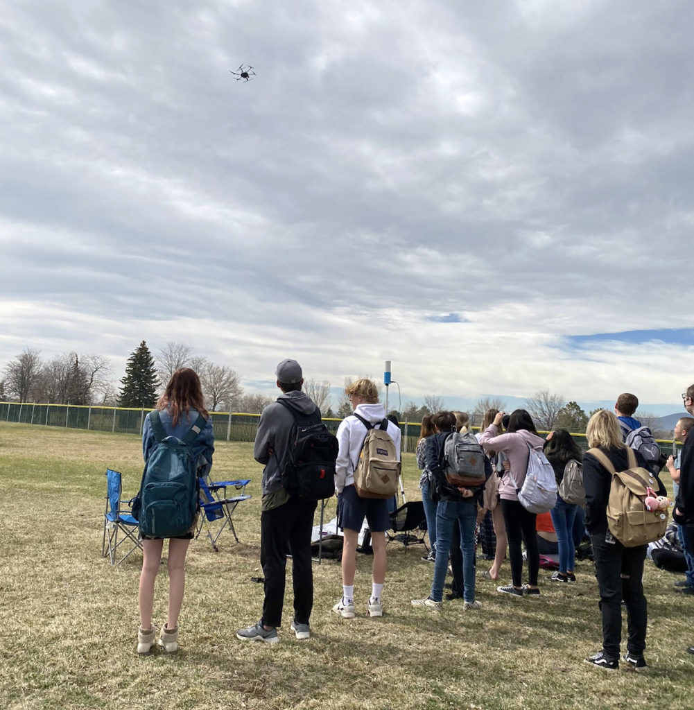 Students observe a drone demonstration outside Loveland High School.