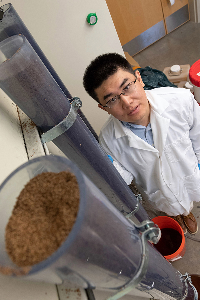 Tiezheng Tong poses for a portrait with some of his lab apparatus.