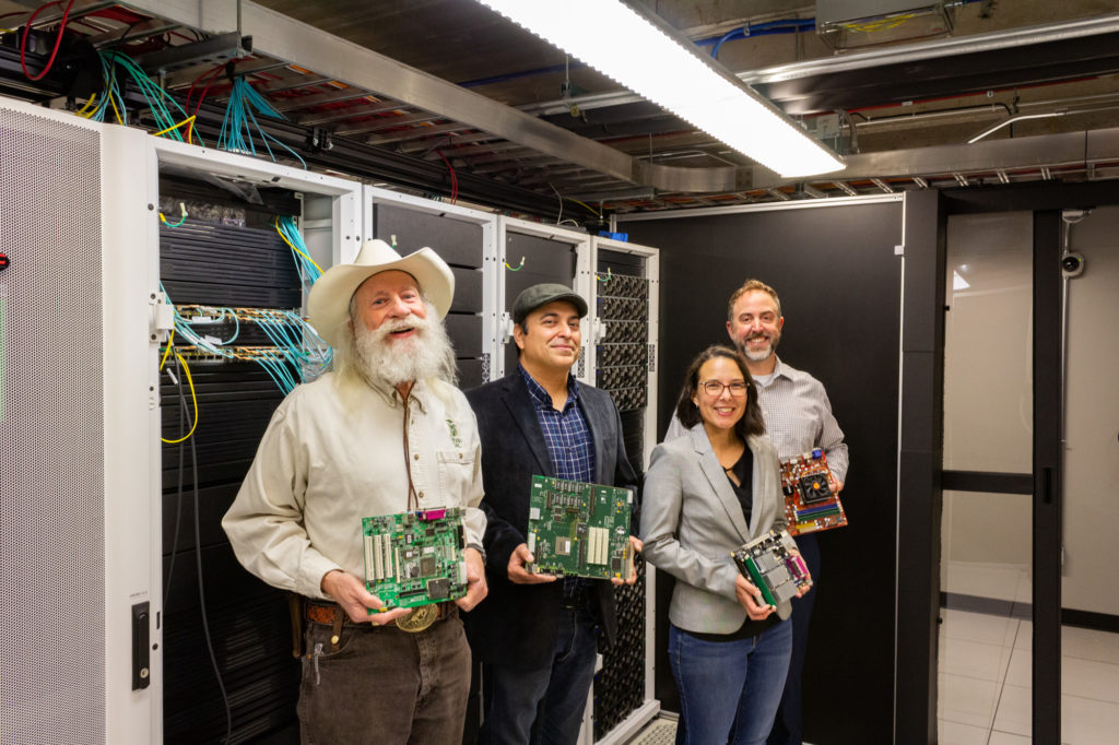 H. J. Siegel, Sudeep Pasricha, Erin Nishimura, and Brandon Bernier pose for a photo in a server environment with computer components.