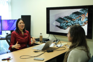 Xinfeng Gao in her office with an undergraduate research assistant . A computational fluid dynamics illustration is visible in the background.