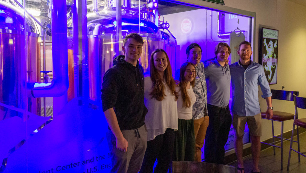CSU engineering students Isaac Reaves (ECE), Kaylee McCarthy-Zayach (CBE), Mackenzie Lucas (CBE), Ethan Ahuna (CBE), and Kyle Curtis (CBE) stand in front of the brewery window in Ramskellar with Jeffrey Callaway, Director of the Fermentation Science and Technology Program, on April 13, 2023.