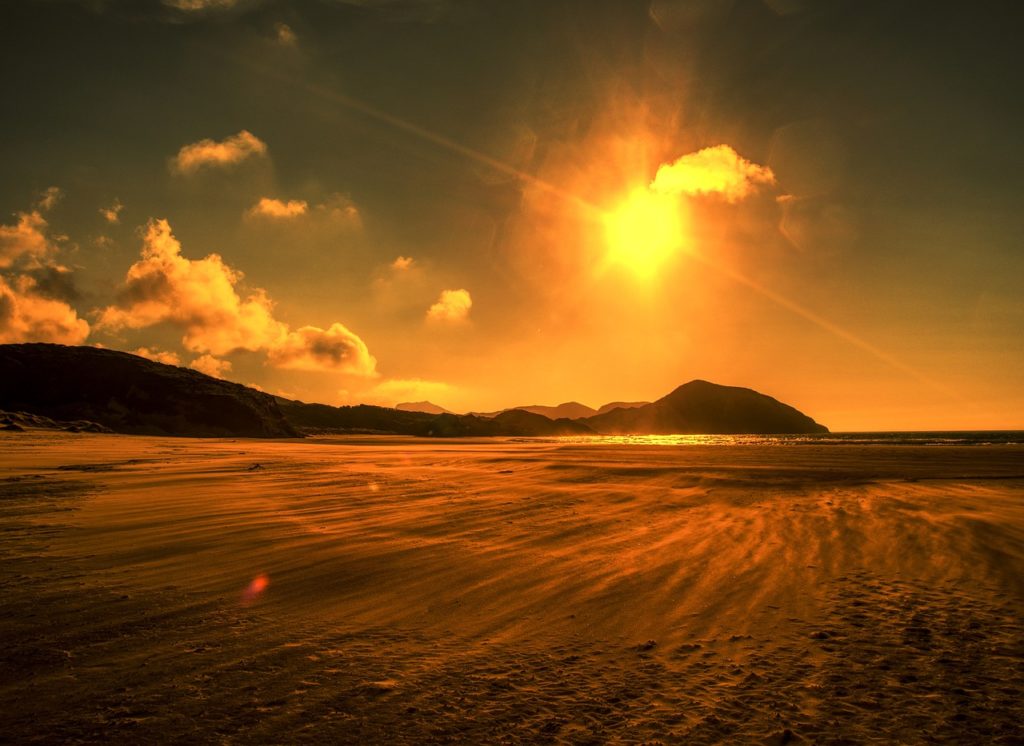 A picture of a hot sun over a beach.
