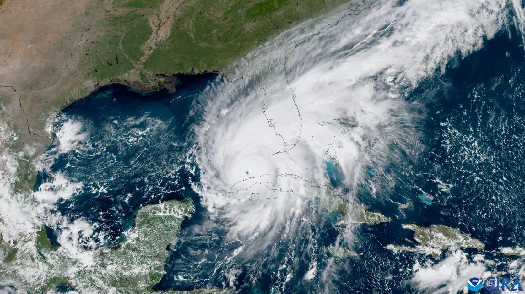 Natural color image of Hurricane Idalia in the southeastern Gulf of Mexico. There is a distinct eye visible just north of Cuba, and the cloud bands trail off into the northeast across the southern United States.