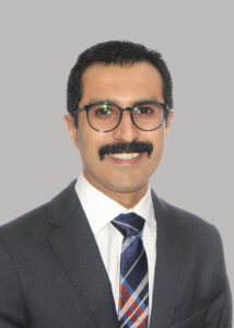 Studio portrait of Kaveh Hassan Rahbardar Mojaver, wearing a suit and tie with a mustache and glasses.