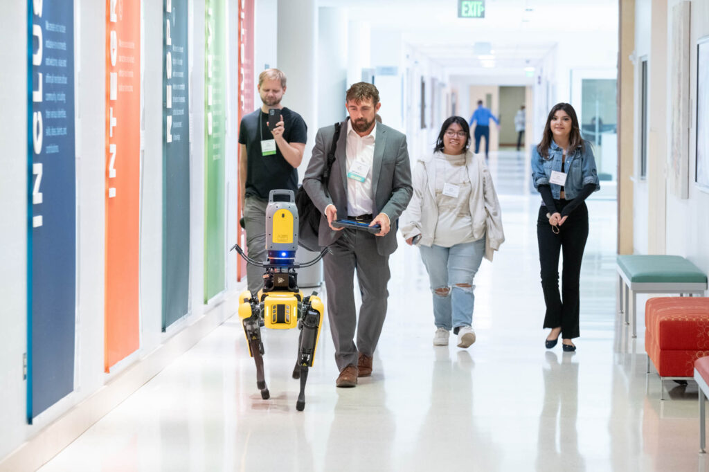Ian Warner, industry workforce director of development and innovation at Trimble Inc., walks to a panel with his robot “dog.”