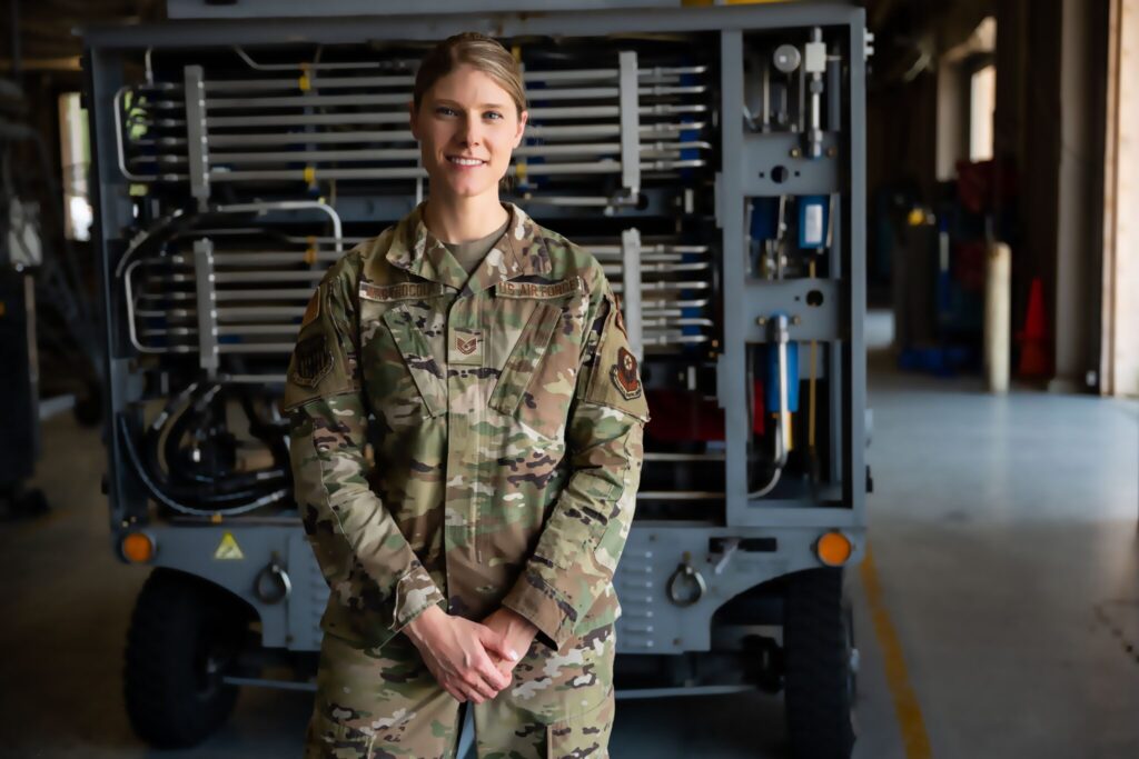 Casual portrait of Tech. Sgt. Mastrocola in a hangar with a piece of support equipment in the background