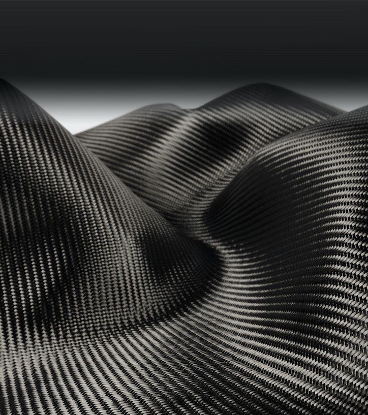 A photograph of a rippled, flowing piece of dry carbon fiber fabric.