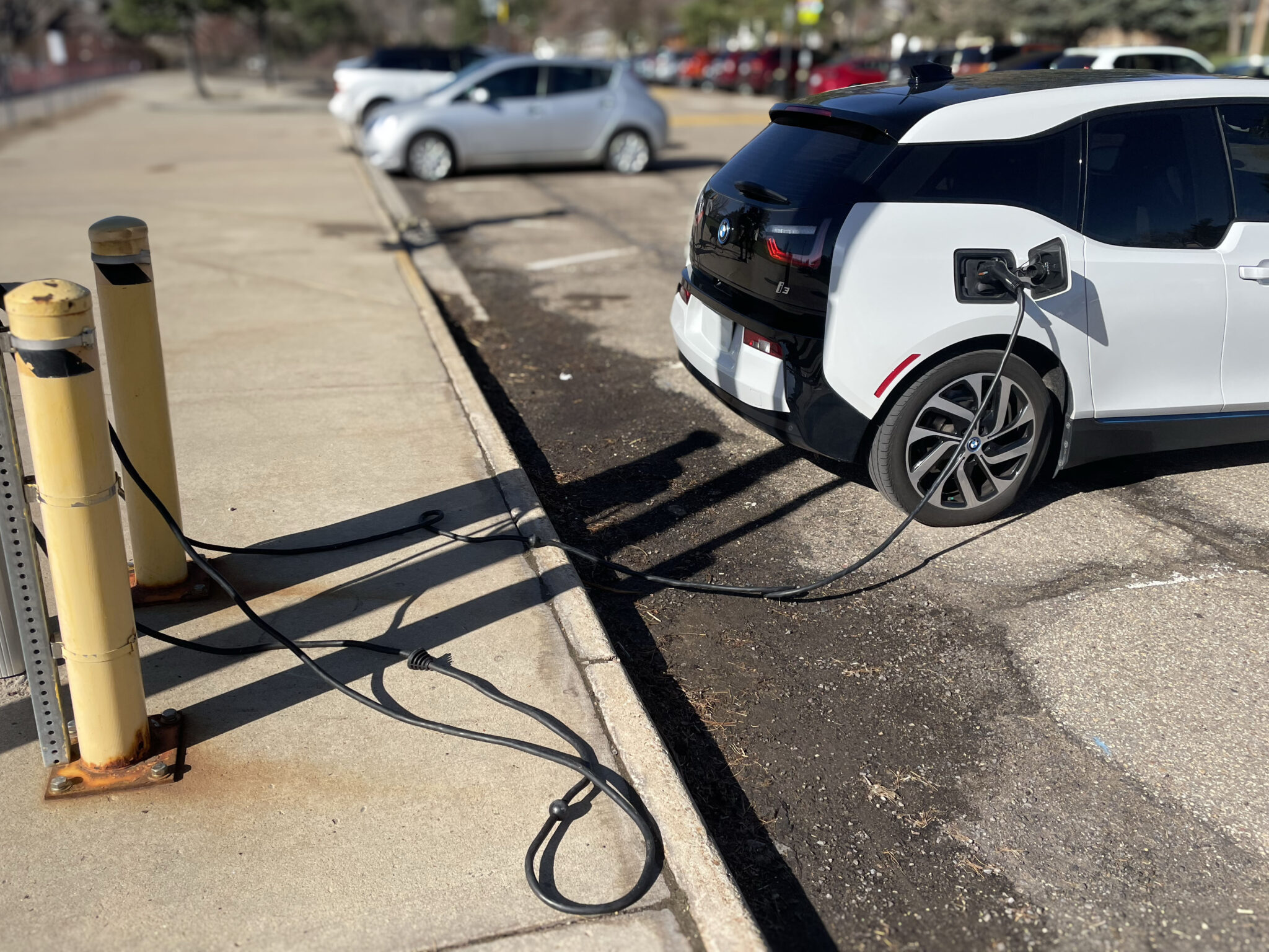 A small car plugged into a electric charging station.