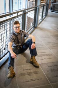 Alex Willman sits on the floor by the engraved tiles.