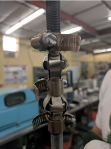A photo of a prototype of the device.  Off-the-shelf hardware components like threaded rod, hex nuts, and stainless steel hose clamps surround the nitinol bands, which are bowed out in the activation configuration.